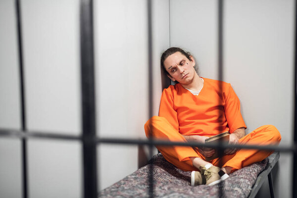 Опасный преступник с татуировками на лице читает книгу стихов, сидящую за решеткой. Встали на путь исправления.