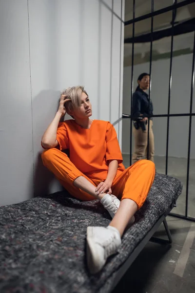 Girl convicted drug dealer in an orange jumpsuit in his cell on a prison bunk — Stock Photo, Image