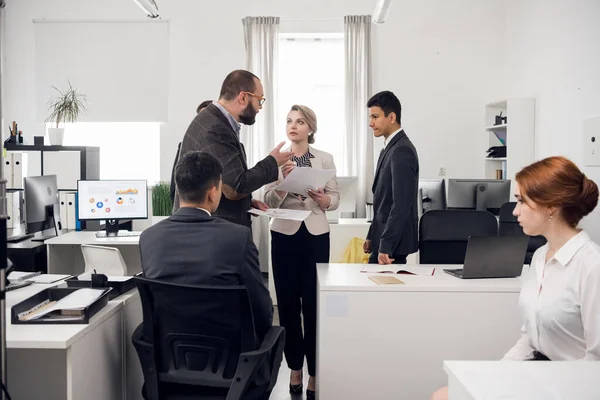 Ein junger Manager übergibt dem Leiter der Personalabteilung im Büro der Leasinggesellschaft Papierdokumente zur Prüfung. — Stockfoto