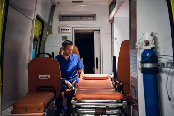 穿着制服坐在救护车上的年轻医生 — 图库照片