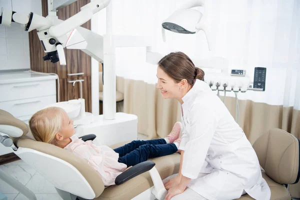 Um jovem dentista sorrindo tendo um pequeno paciente — Fotografia de Stock
