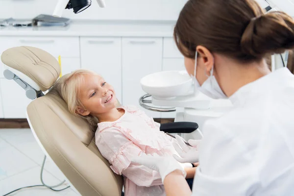 Un dentista experimentado está sentado cerca de la chica tratando de establecer — Foto de Stock