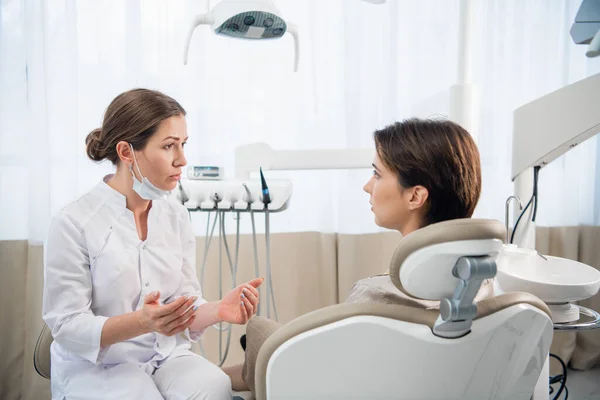 Una dentista consultando a su paciente en la clínica — Foto de Stock