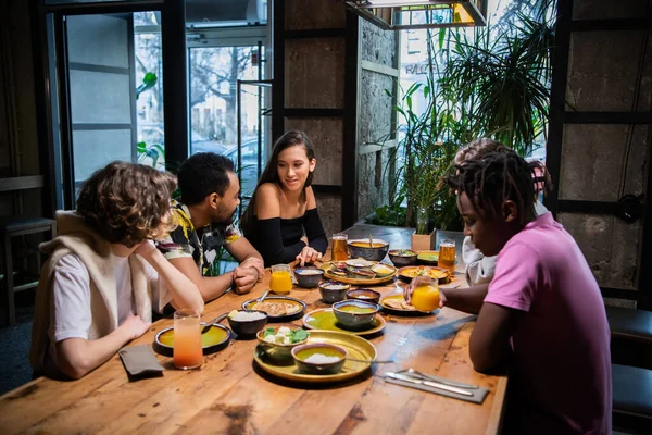 Een multiculturele groep studenten in een café, die Aziatisch eten eten, — Stockfoto