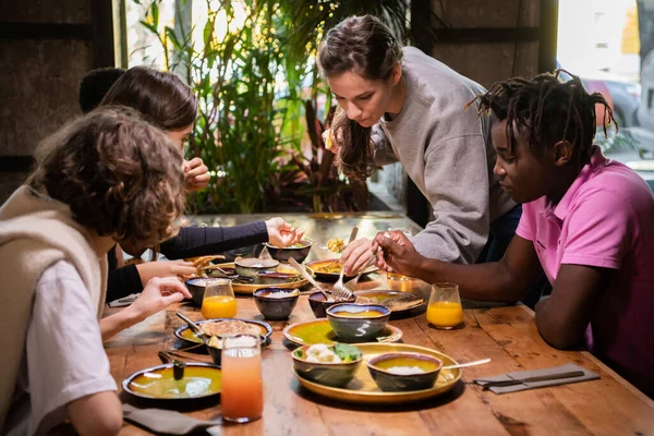 Un groupe multiculturel d'étudiants partageant de la nourriture dans un café — Photo