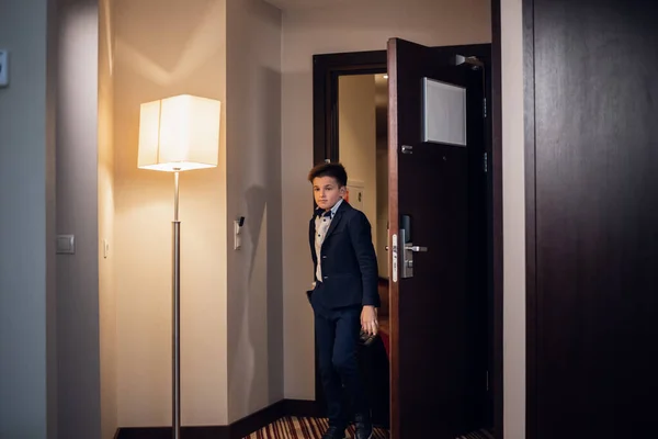 Mladý chlapec ve slavnostním oděvu vstupuje do hotelového pokoje — Stock fotografie