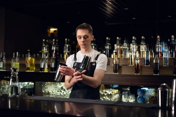 A young bartender hosts a show with shakers at the bar in a nightclub — Stock Photo, Image