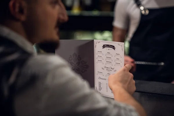 Чоловік читає меню в барі, крупним планом меню і руках — стокове фото