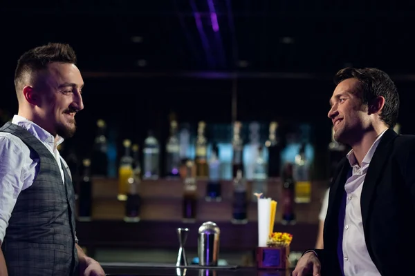 two male friends meet at the bar at the counter and communicate