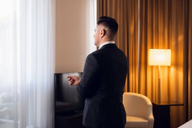 Genç bir iş adamının ayakta dururken kelepçelerini düzeltirken çekilmiş bir fotoğrafı.