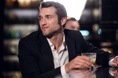 Bir barda elinde kokteyl, portre ve yakın çekim olan gömlek ve ceket giymiş yakışıklı bir adam.