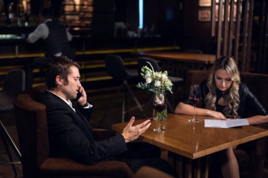 Genç bir işadamı iş sorunlarını telefonda çözer. Arkadaşı menüden yemek seçer.