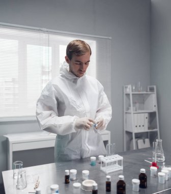 Laboratuvarda kimyasal test yapan bir araştırmacı bazı maddeleri karıştırıyor.