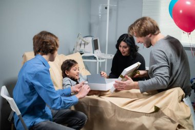 Hastane koğuşunda bir doğum günü partisi, küçük bir kız hediyeler alıyor.