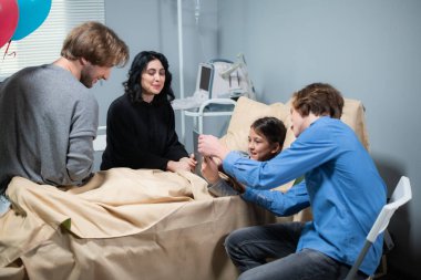 Küçük mutlu bir kız hastanede yatarken tablet kullanmayı öğreniyor. Ağabeyi de ona yardım ediyor.