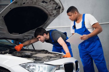 Mühendisler bir otomobili tamir edip rapor yazıyorlar.