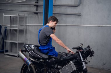 Bir tamirci bisiklette oturmuş müşteriye sesleniyor.