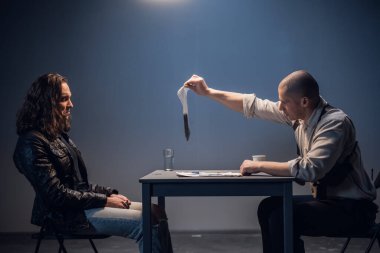 Uzun saçlı alıkonulmuş bir beyaz adam, suçunun inkar edilemez kanıtını karakoldaki bir müfettişten aldı.