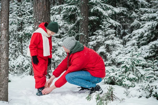 Os sapatos dos meninos são desabotoados, o homem de zíper na floresta de inverno durante uma caminhada — Fotografia de Stock