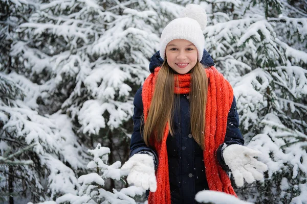 Молодая девушка-подросток в пуховике красиво улыбается для фотографии в зимнем заснеженном лесу — стоковое фото
