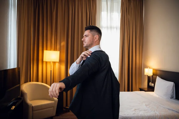 A young businessman dressing up in a fancy hotel room