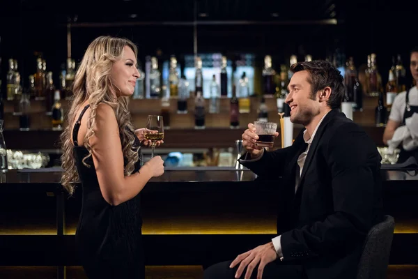Μια νεαρή ξανθιά γυναίκα και ένας επιτυχημένος άντρας μιλάνε στο μπαρ σε ένα εστιατόριο, πίνοντας κοκτέιλ. — Φωτογραφία Αρχείου