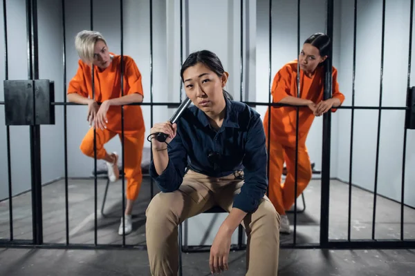 Prisión de mujeres asiáticas. En la celda hay dos niñas condenadas por un delito penal y una mujer guardiana con uniforme de guardia. — Foto de Stock