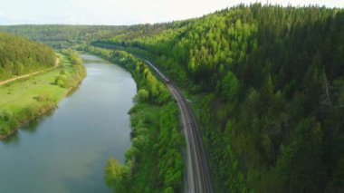Tren nehri ve yeşil üzerinden geri uçuyor.