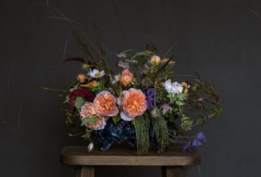 Gri odadaki ahşap sandalyede güllerle dolu buket. 