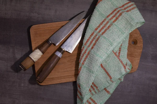 Tow Big kitchen knife with wood and ivory handle lying on an old cutting board and kitchen rag