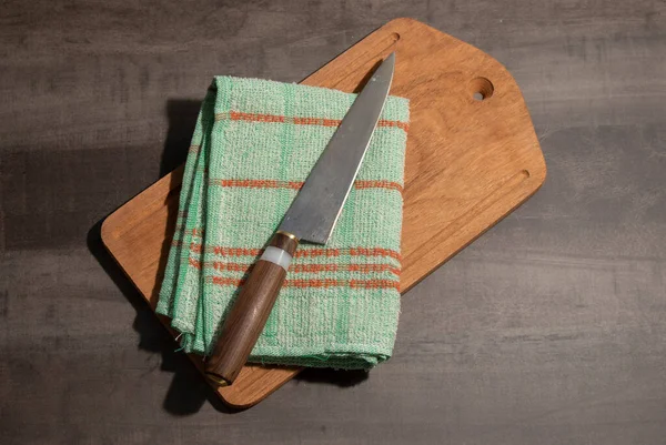 Big kitchen knife with wood and ivory handle lying on an old cutting board and kitchen rag