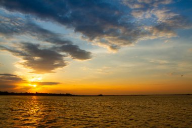 Güneşin ufukta göründüğü güzel gün batımı göldeki altın ışığı yansıtıyor..