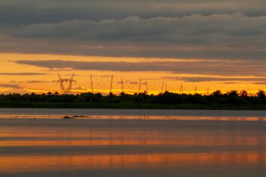 Güneşin ufukta göründüğü güzel gün batımı göldeki altın ışığı yansıtıyor..