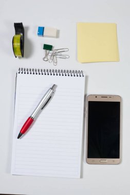 Ofis eşyaları ve iş unsurları cetvel, kalem, silgi, kalem açacağı, not defteri, mektup açacağı, ataç, makas, zımba zımbası, kanca çıkarıcı, sd hafıza kartı, yapıştırıcı bant, cep telefonu, usb kablosu, keski, yaratıcı kavram kavramı gibi bir masanın üzerinde.