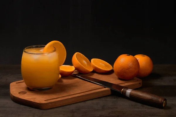Освежающий Стакан Свежим Апельсиновым Соком Льдом Апельсинами Деревянном Столе Темном — стоковое фото