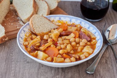 Madrid, İspanya 'nın tipik mutfağının tabağı. Mondongo a la espanola ya da cayos a la espanola. İşkembe, et, sucuk, nohut ve sebze ve domates soslu patatesten yapılmış. Tahta bir masanın üzerinde mavi aksanlı beyaz bir vintage plakada sunuluyor.