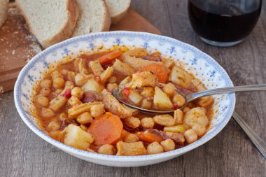 Madrid, İspanya 'nın tipik mutfağının tabağı. Mondongo a la espanola ya da cayos a la espanola. İşkembe, et, sucuk, nohut ve sebze ve domates soslu patatesten yapılmış. Tahta bir masanın üzerinde mavi aksanlı beyaz bir vintage plakada sunuluyor.