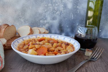 Madrid, İspanya 'nın tipik mutfağının tabağı. Mondongo a la espanola ya da cayos a la espanola. İşkembe, et, sucuk, nohut ve sebze ve domates soslu patatesten yapılmış. Tahta bir masanın üzerinde mavi aksanlı beyaz bir vintage plakada sunuluyor.