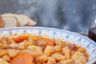 Madrid, İspanya 'nın tipik mutfağının tabağı. Mondongo a la espanola ya da cayos a la espanola. İşkembe, et, sucuk, nohut ve sebze ve domates soslu patatesten yapılmış. Tahta bir masanın üzerinde mavi aksanlı beyaz bir vintage plakada sunuluyor.