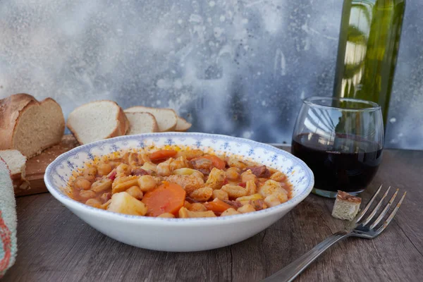 Madrid, İspanya 'nın tipik mutfağının tabağı. Mondongo a la espanola ya da cayos a la espanola. İşkembe, et, sucuk, nohut ve sebze ve domates soslu patatesten yapılmış. Tahta bir masanın üzerinde mavi aksanlı beyaz bir vintage plakada sunuluyor.