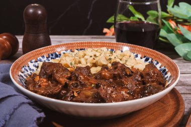 Paprikayla tatlandırılmış spaetzle güveç ve geleneksel bir Macar yemeği olan kırmızı şarapla servis edilir.