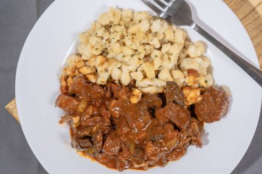 Beyaz tabakta spaetzle etli biftek, geleneksel Macar mutfağını temsil ediyor.