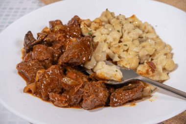 Lezzetli bir tabak gulaş ve spaetzle 'den çatal kaldırma spatulası. Geleneksel bir Avustralya yemeği.