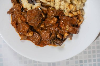 Bir tabak et gulaş güvecinden çatal kaldırmak, doyurucu ve lezzetli bir yemek.