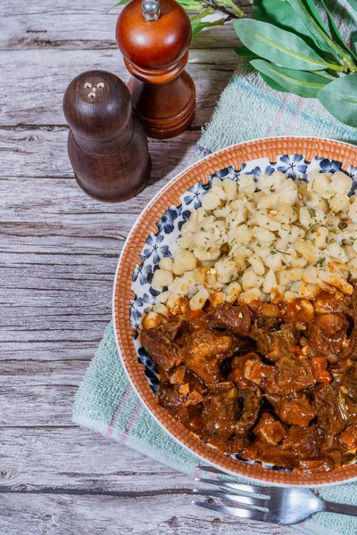 Makarna köfteleriyle servis edilen doyurucu bir tabak Macar gulaşı, rahatlatıcı ve lezzetli bir yemek yaratıyor.