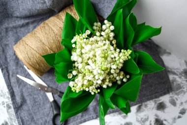 Çiçekçi dükkanında elinde makasla bir buket zambak, beyaz çiçekler ve yeşil yapraklar.