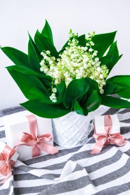 Beyaz kovada vadideki nilüferlerin buketi şimdiki kutular ve beyaz bir masada fotokopi alanı olan pembe kurdeleler. Tatil geçmişi kavramı, evde bahar çiçekleri