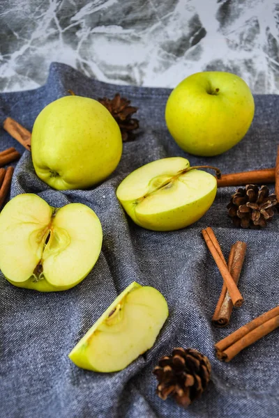 green golden apples or Granny smith with cinnamon sticks pine fir cones on kitchen towel, preparing food, dessert, healthy nutrition, autumn time