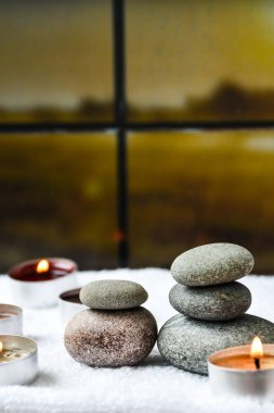 Zen konsepti, spa çakıl taşları ve bulanık arka planda yanan aroma mumları, aromaterapi ve masaj, metin için kopyalama alanı