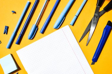 Not defterlerinden beyaz kare kağıt, ahşap renkli mandal, ataç, metin için kopya alanı, okula dönüş konsepti, kırtasiye ofis malzemeleri, üst görünüm